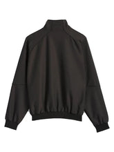 A black lightweight bomber jacket with a mock neck, raglan sleeves, and elasticized cuffs and hem, shown from the back on a light gray background.