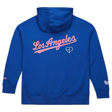 A royal blue hoodie shown from the back, featuring 'Los Angeles' in pink script with a white heart outline and a white script logo on the left sleeve cuff, set against a light off-white background.