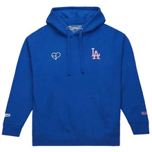 A royal blue pullover hoodie with a drawstring hood and kangaroo pocket, featuring a white heart outline logo on the left chest and an 'LA' logo in white and red on the right chest, on a light beige background.