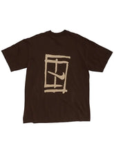 A dark brown short-sleeve t-shirt with a beige graphic print on the front, featuring a stylized window frame and a Nike swoosh, displayed against a light gray background.