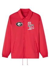 A red Coach jacket featuring the Georgia Bulldogs logo on the left chest and the iconic Coach owl logo on the right chest, displayed against a neutral gray background.