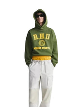 Person wearing a green hoodie with 'R.H.U' branding on a gray background